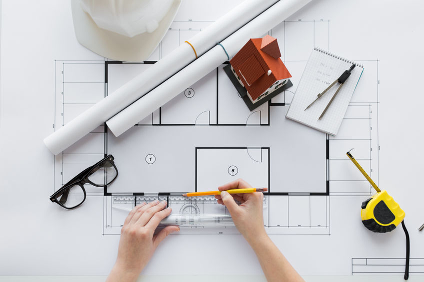 close up of hands with ruler measuring blueprint